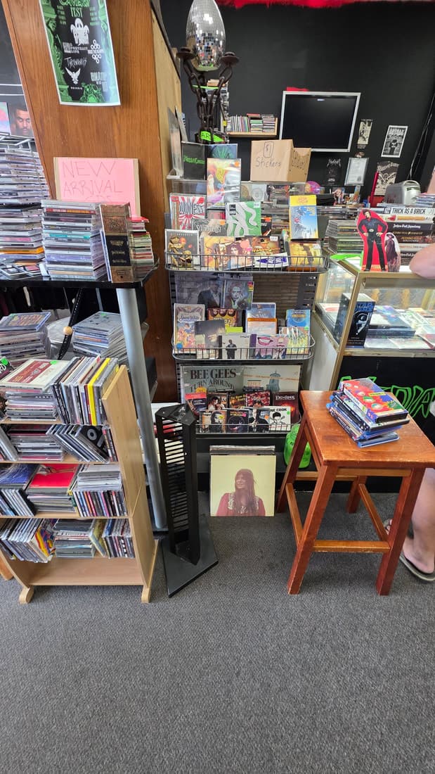 New-arrivals CD racks in the corner with a disco ball overhead; a customer partly in frame