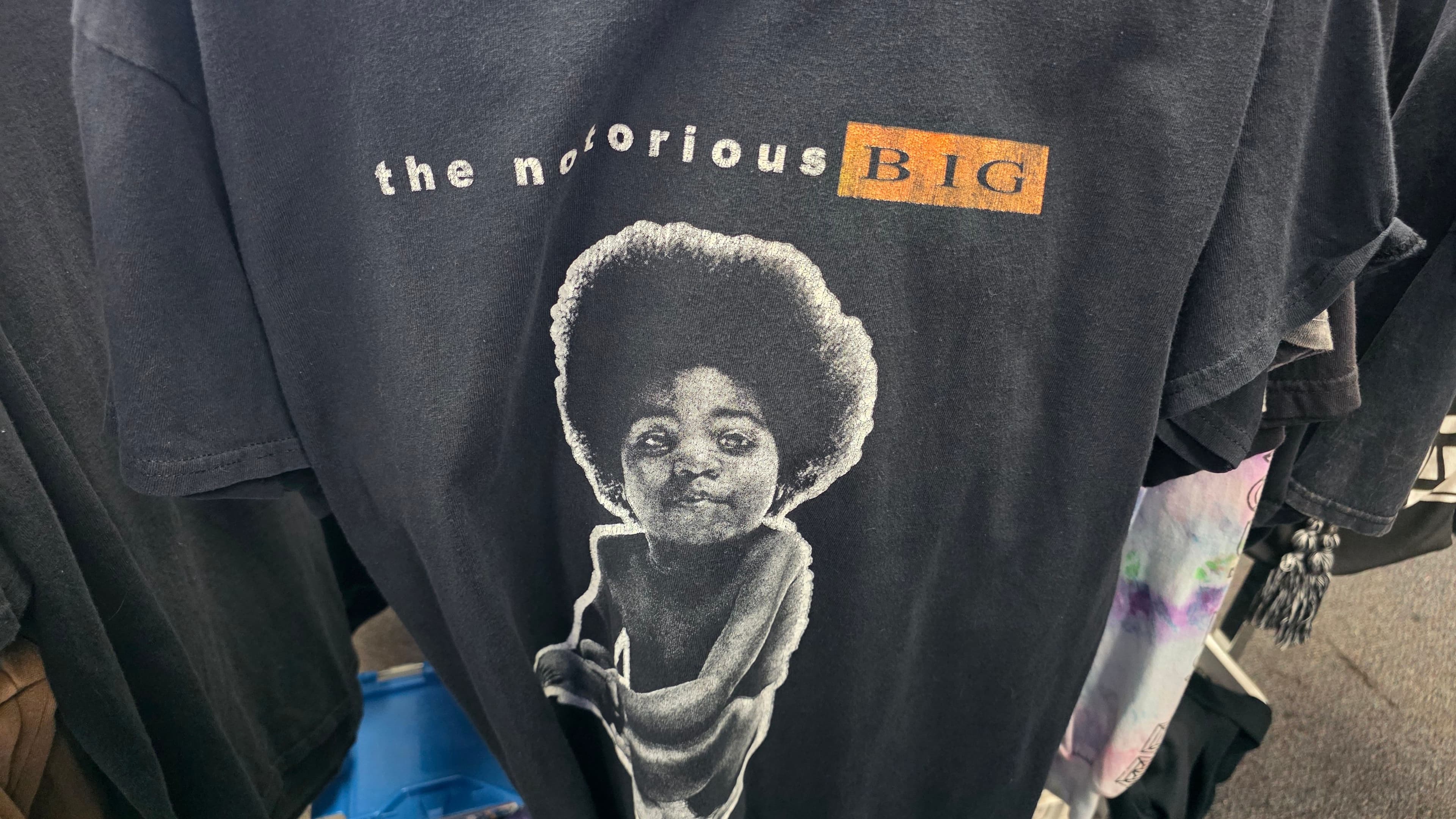 A black Notorious B.I.G. tee on the rack, childhood portrait printed large across the chest