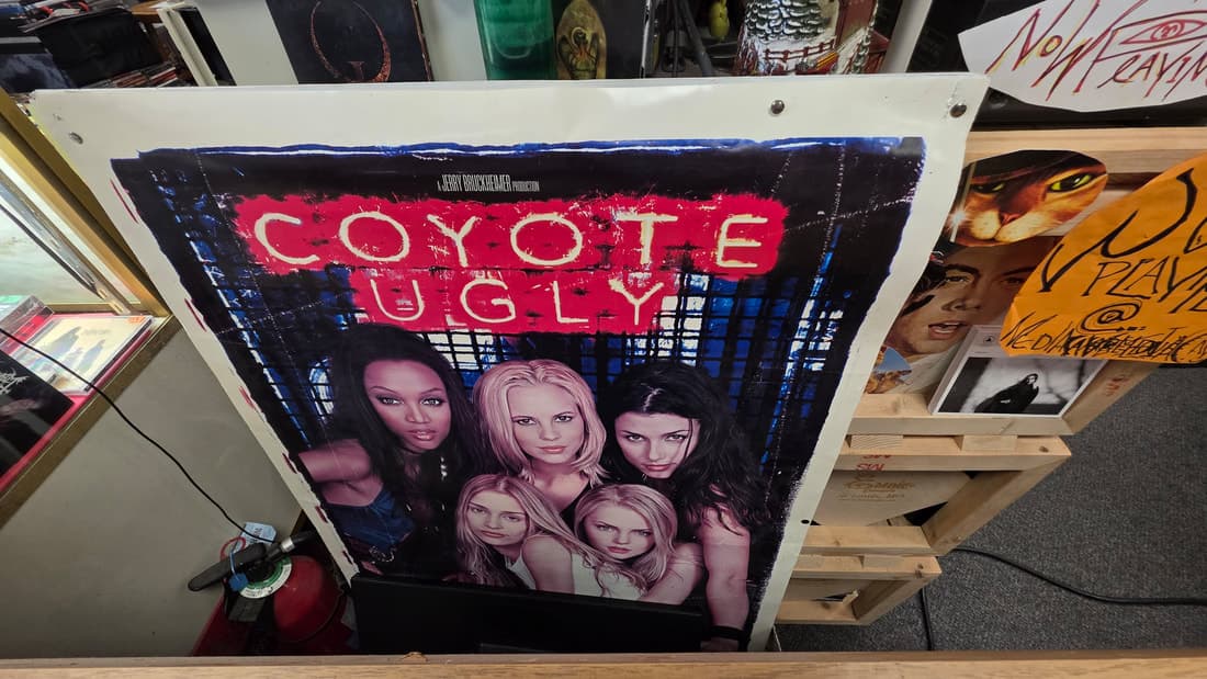 Coyote Ugly movie poster propped on the counter beside stock
