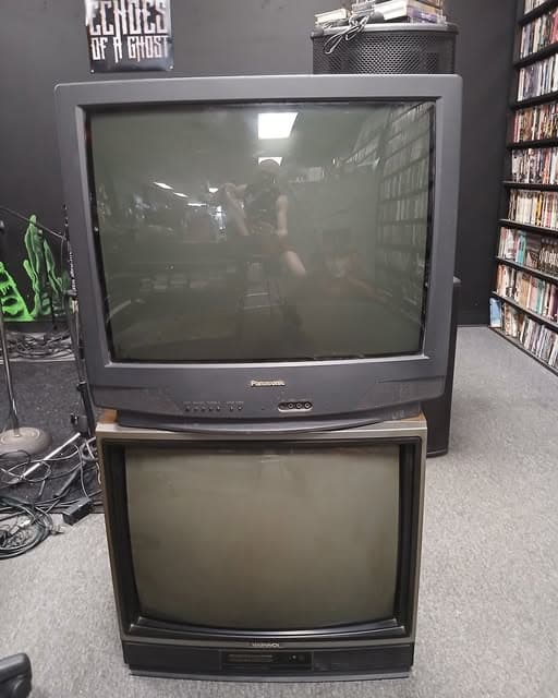 Two stacked CRT televisions, the top one showing a band performing, beneath an Echoes of a Ghost banner