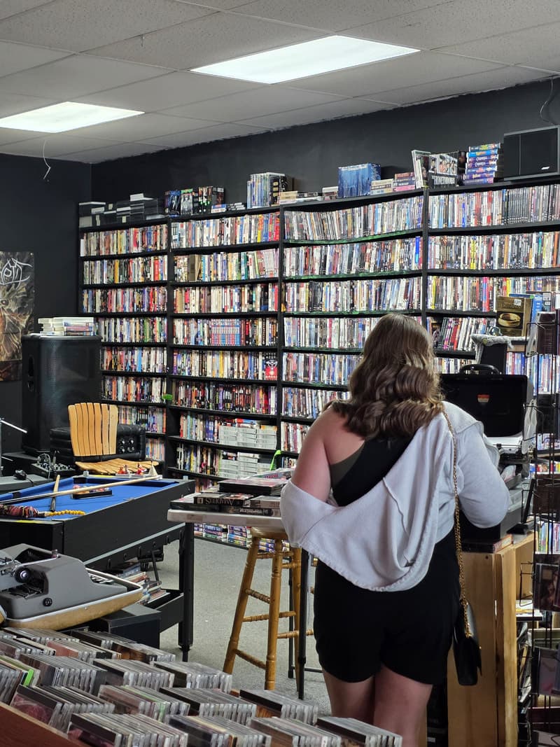 Customer at the counter in front of the full-height DVD wall, pool table and typewriter in the foreground