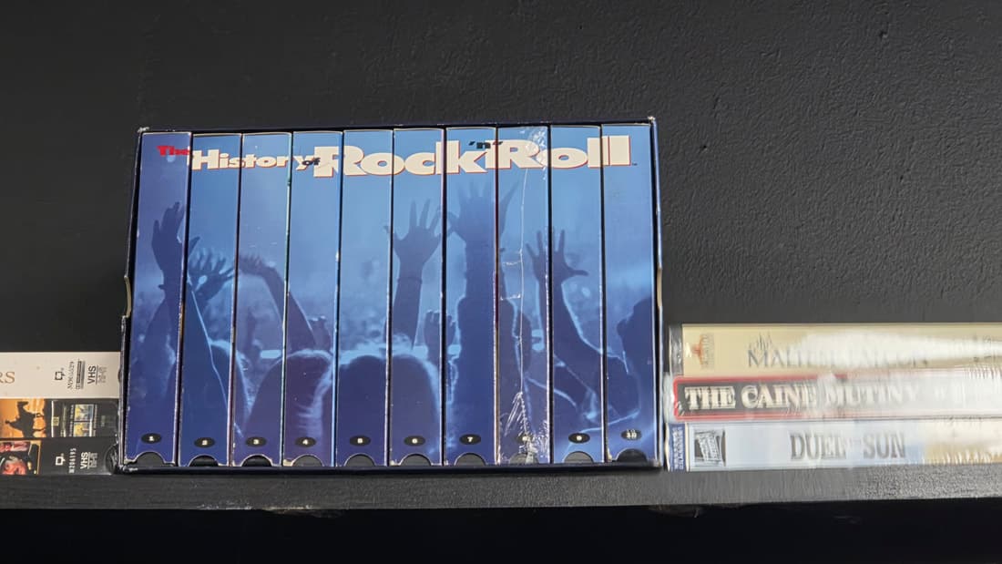 The History of Rock 'n' Roll VHS box set on a shelf among other tapes