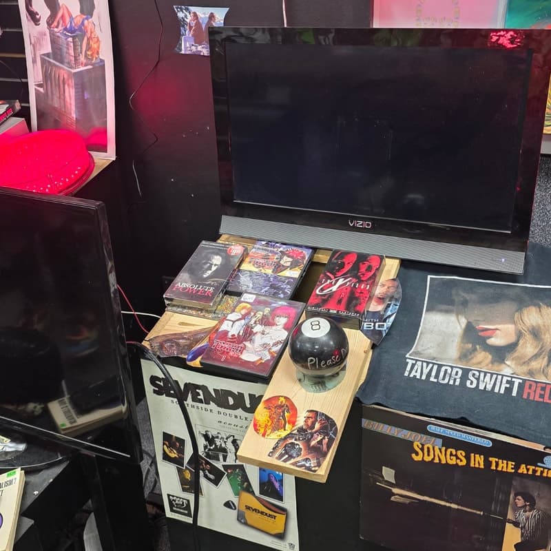 Shelf of oddities: VHS tapes, a Magic 8-Ball, a Taylor Swift Red tee, a Billy Joel LP and a Sevendust poster