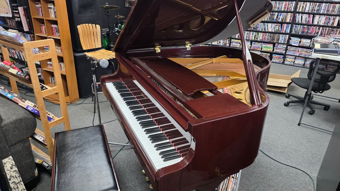 Wider framing of the mahogany grand piano with surrounding shelving