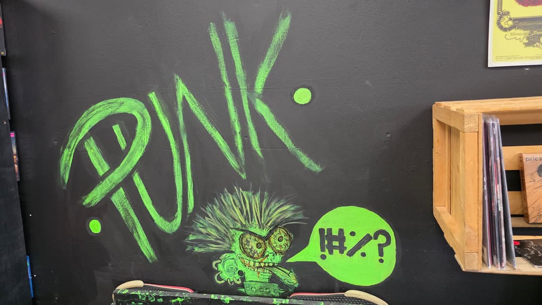 Wider frame of the green PUNK chalk mural with a skate deck and vinyl crate beside it