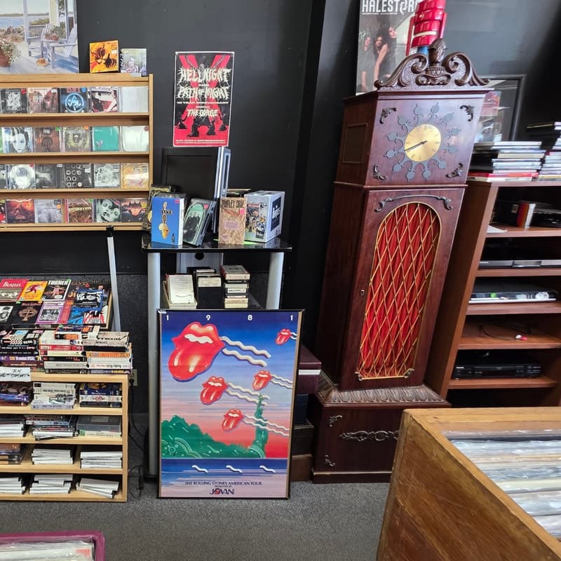 Rolling Stones 1981 tour poster above cassette and 8-track bins beside a grandfather clock
