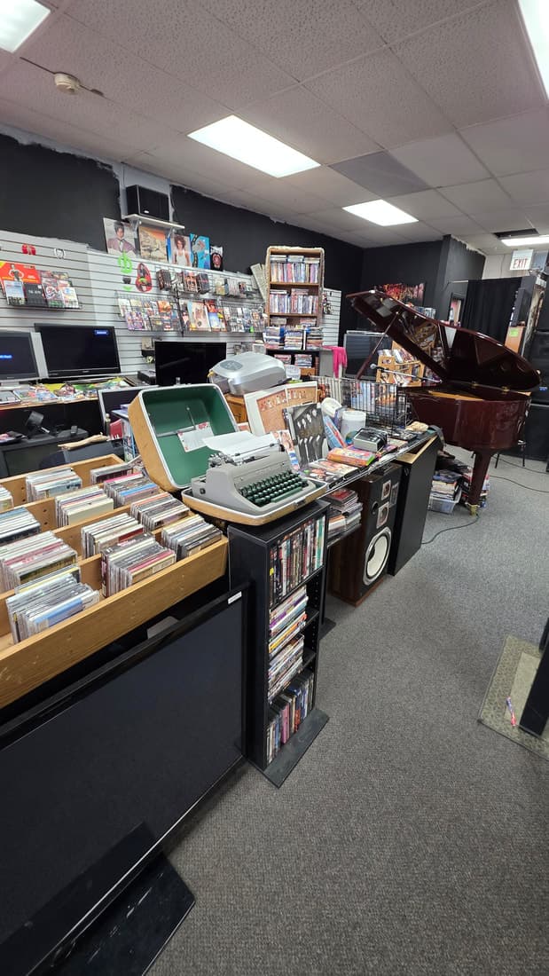 Tall interior view taking in the CD bins, typewriter, grand piano and slatwall in one frame