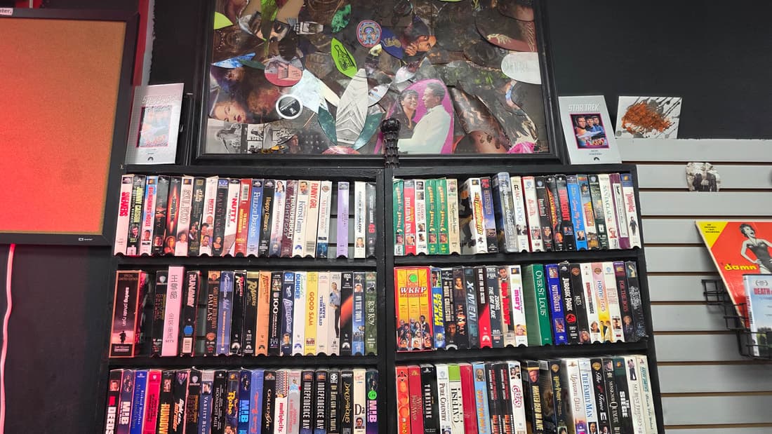VHS shelving wall with the collage artwork panel above it