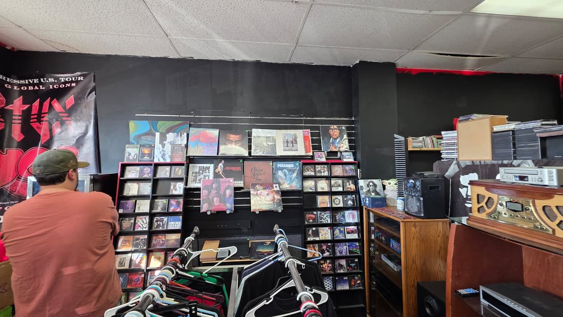 Vinyl and CD slatwall under a Styx tour banner with a jukebox-style radio; a customer in frame